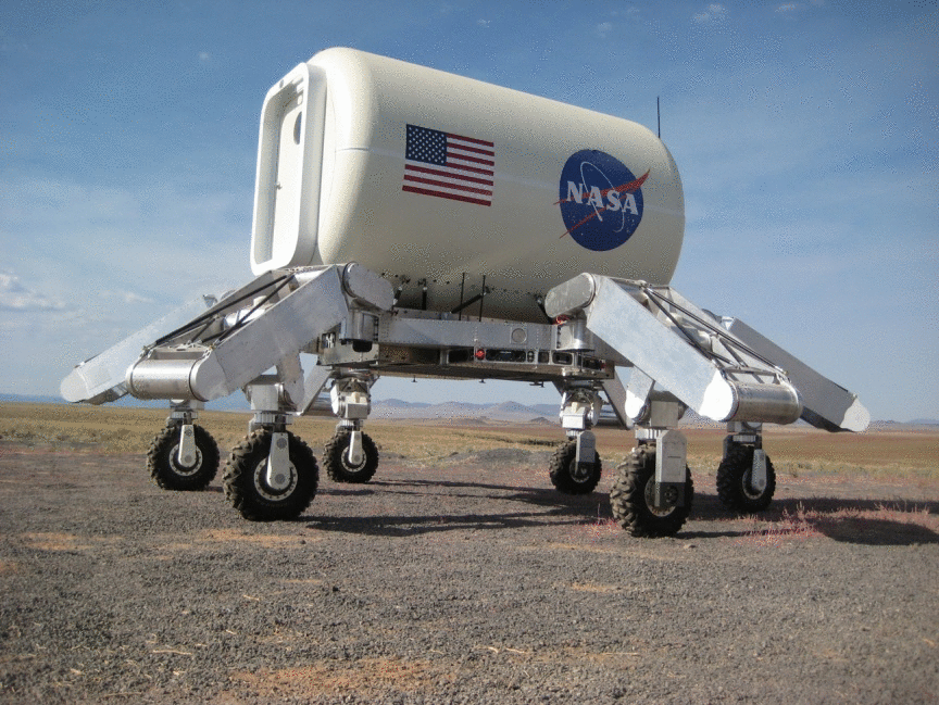 ATHLETE SDM-T12 in the field carrying a pressurized habitat mock-up. The six wheels sit at the ends of six seven-degree-of-freedom limbs, and the two triangular three-limbed Tri-ATHLETE halves are docked to a shared cargo pallet under the payload