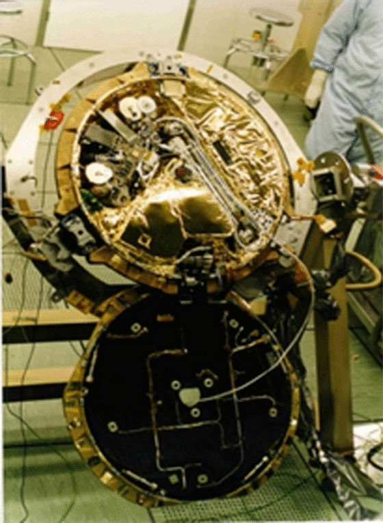 Beagle 2 lander at the Airbus Stevenage facility before integration with Mars Express, lid open. The base section is about 0.7 m in diameter and holds the instruments; the solar panels are stowed in the lid. The stowed ARM and the PAW occupy the upper right of the base