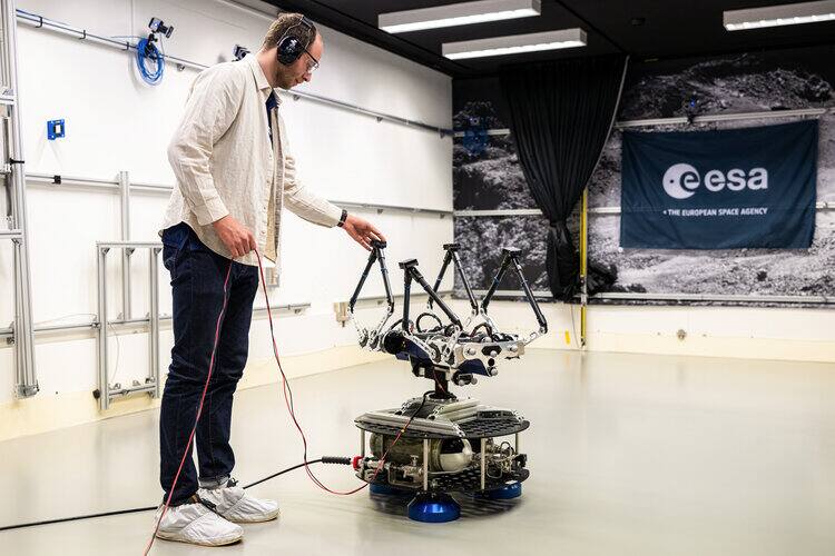 The NTNU quadruped Olympus mounted on an ORBIT floating platform, with its three air bearing pads and pressure vessel visible under the deck, on the epoxy flat floor at ESTEC.