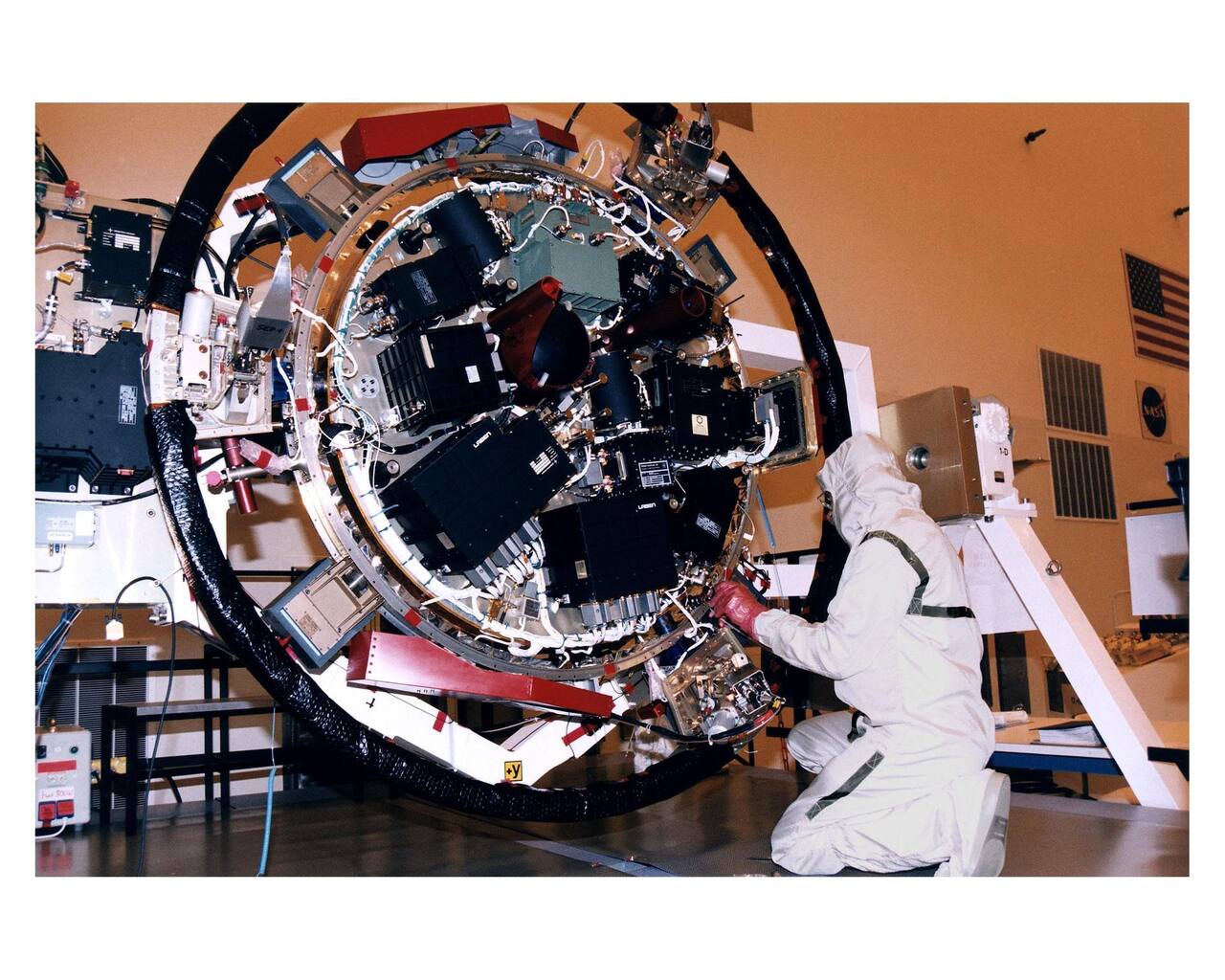 The Huygens descent module under integration at NASA KSC in April 1997, with the front shield and back cover removed. Every one of the six instruments and its support electronics is mounted on the single experiment platform seen here, which then went inside a sealed, insulated shell. The probe massed 318 kg complete, of which 79 kg was the front shield and about 16 kg the back cover