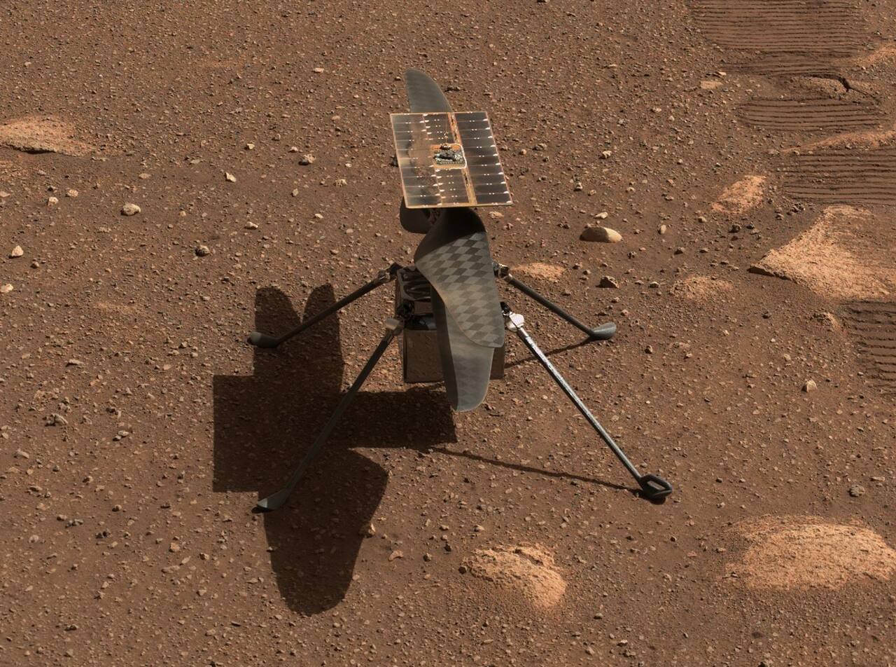 Ingenuity on the surface of Jezero crater, photographed by the Perseverance Mastcam-Z zoom cameras on sol 45, 5 April 2021, shortly after deployment from the rover's belly. The four blades of the coaxial counter-rotating rotor, the square solar panel above the rotor hub and the four landing legs are the whole vehicle; the fuselage between the legs holds the batteries and avionics