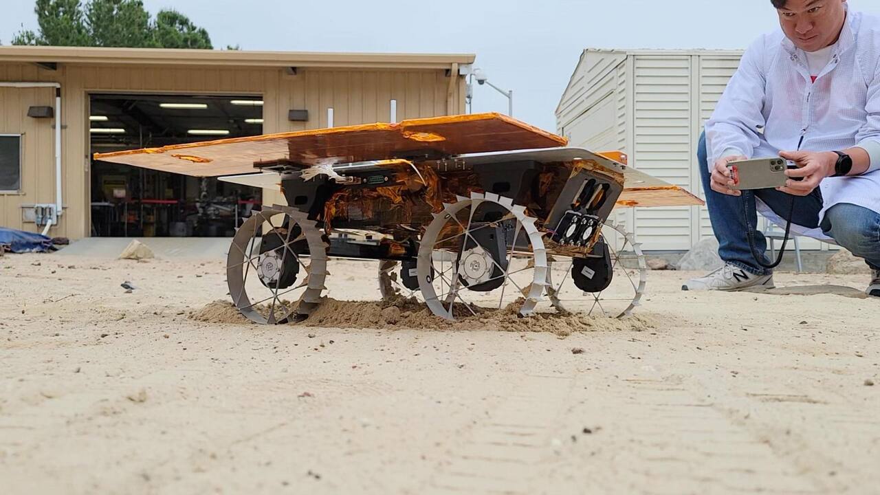 A CADRE development model rover during its first autonomous drive in the Mars Yard at NASA JPL, June 2023, with engineer Kristopher Sherrill recording video of the test.