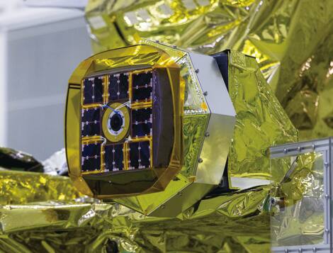LEV-1 in its stowed configuration mounted on the SLIM spacecraft before launch. The body face carries the solar cell array around a central camera aperture, and the gold multilayer insulation of the surrounding structure fills the frame