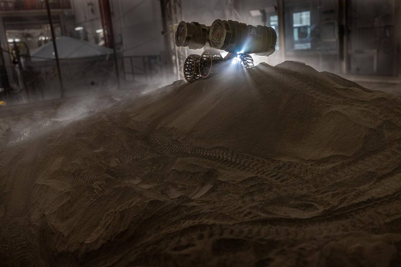 RASSOR building a three-foot berm from simulated regolith during a site preparation test in the Granular Mechanics and Regolith Operations Lab at NASA KSC, 3 June 2025. The two bucket drums are carried on opposing arms either side of the chassis; their opposing rotation is what lets the machine dig without needing traction to react the cut