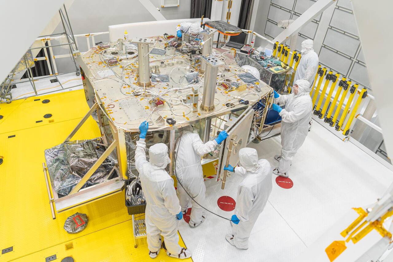 OSAM-1 flight hardware under integration in NASA GSFC clean room on 14 September 2023, six months before NASA discontinued the mission. The hexagonal deck carries the cable runs and mounting interfaces of the servicing spacecraft, with a side panel being fitted at right; the robotic arms are not installed at this stage